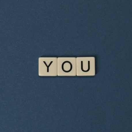 you is written in scrabble tiles on a plain blue background